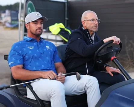 Bryson DeChambeau heads back to the 5th with R&A director Grant Moir.