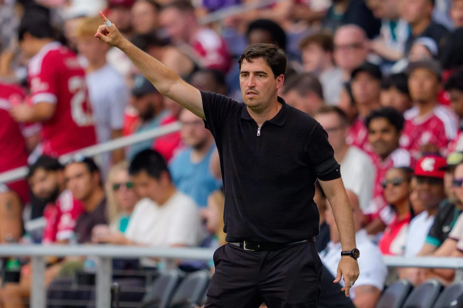 A football coach in a navy shirt points from the sideline