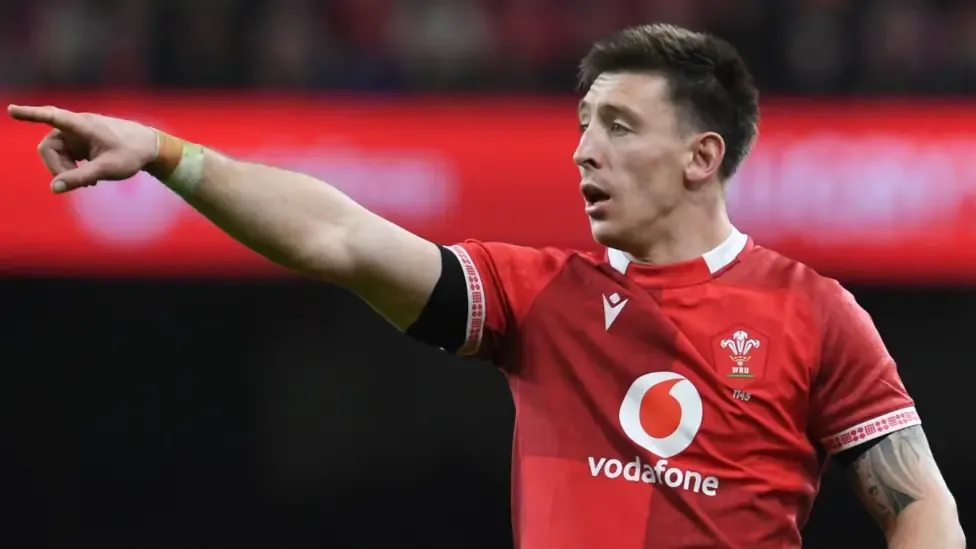 Josh Adams in the red jersey of Wales points with outstretched right arm