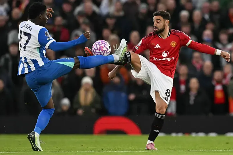Manchester United's Portuguese midfielder #08 Bruno Fernandes (R) and Brighton's Cameroonian midfielder #17 Carlos Baleba (L) battle for the ball