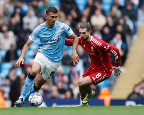 Manchester City's Rodri holds off Liverpool's Szoboszlai while controlling the ball
